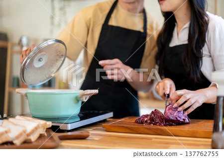 Close up couple man open pot and woman girlfriend cutting vegetable cooking food at kitchen counter. 137762755