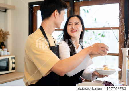 Asian couple a boyfriend holding hands with a woman girlfriend over pasta plate at kitchen counter. Asian couple a boyfriend holding hands with a woman girlfriend over pasta plate at kitchen counter. 137762780
