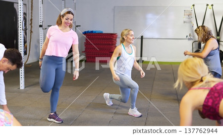 Group of women exercising and stretching in a gym with trainer 137762944