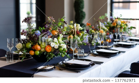 Lavish banquet table decor featuring vibrant floral centerpieces with seasonal fruits and elegant place settings 137762971