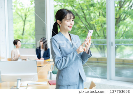 在辦公室使用智能手機的女商人 在辦公室使用智能手機的女商人 137763698