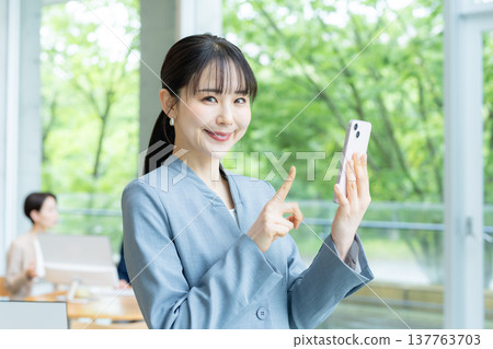 在辦公室使用智能手機的女商人 在辦公室使用智能手機的女商人 137763703