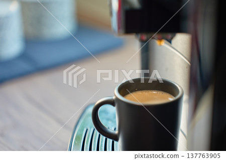 Black cup with fresh espresso on coffee machine drip tray. Morning coffee Black cup with fresh espresso on coffee machine drip tray. Morning coffee 137763905