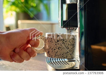 Person takes cup of freshly brewed coffee from coffee machine 137763906