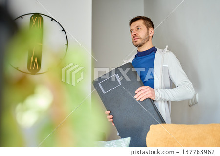 Man holding exercise mat indoors preparing for home workout 137763962