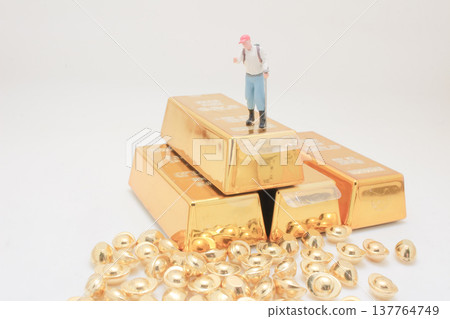 Miniature explorer stands proudly atop stacked shining gold bars 137764749