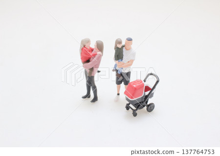 Miniature family stands together beside stroller on white Miniature family stands together beside stroller on white 137764753