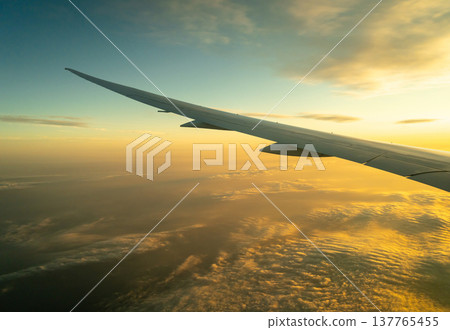 Airplane wing above the clouds during golden hour flight Airplane wing above the clouds during golden hour flight 137765455