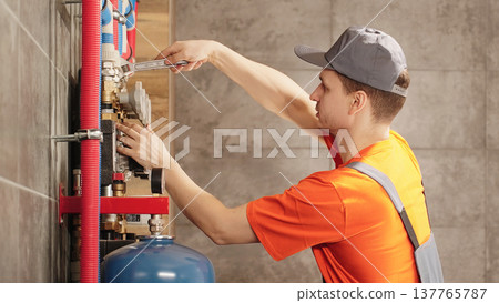 Professional Plumber Or HVAC Technician Repairing Heating Pipe Connection With Wrench In Residential Boiler Room During Plumbing And Heating System Maintenance 137765787