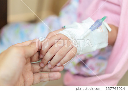 Mother holding child hand with saline IV solution in hospital Mother holding child hand with saline IV solution in hospital 137765924