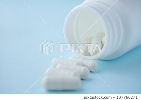 medicine pills capsule spilling out of bottle on blue background 137766271