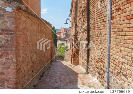 Empty narrow street in a historic European town with outdoor cafe tables. Stone walls, warm tones and calm morning atmosphere. Travel, architecture and slow life concept, Certaldo, Italy Empty narrow street in a historic European town with outdoor cafe tables. Stone walls, warm tones and calm morning atmosphere. Travel, architecture and slow life concept, Certaldo, Italy 137766689