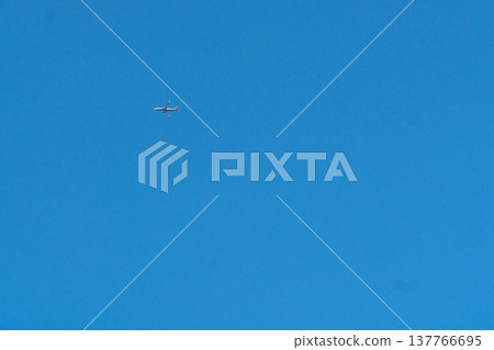 Minimal blue sky with small airplane in flight. Strong visual metaphor for freedom, business travel, aviation industry, global mobility, and lifestyle advertising. Minimal blue sky with small airplane in flight. Strong visual metaphor for freedom, business travel, aviation industry, global mobility, and lifestyle advertising. 137766695