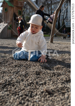 Toddler playing on gravel playground in sunny park Toddler playing on gravel playground in sunny park 137767013