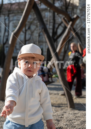 Toddler in white hoodie at playground on sunny day 137767014