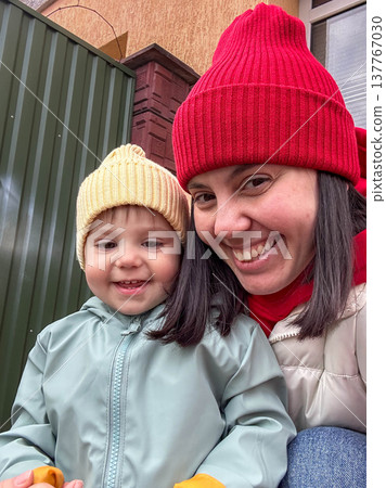 Smiling mother and toddler in winter beanies outdoor selfie Smiling mother and toddler in winter beanies outdoor selfie 137767030
