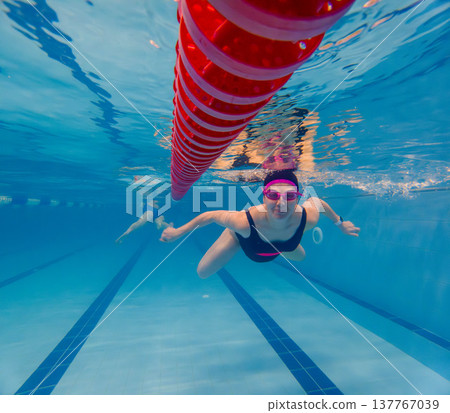 Underwater swimmer training in pool beside red lane line 137767039