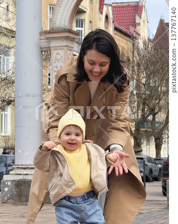 Mother holding toddler on city street in spring 137767140