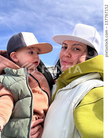 Mother holding toddler outdoors under blue sky Mother holding toddler outdoors under blue sky 137767152