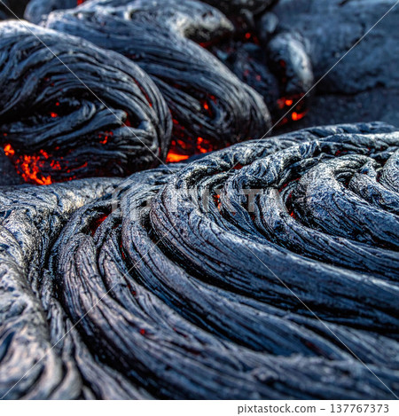 Explore the intense beauty of volcanic activity with this macro of cooling lava. Its ropey texture and glowing red core evoke primeval energy, perfect for nature and science themes. 137767373