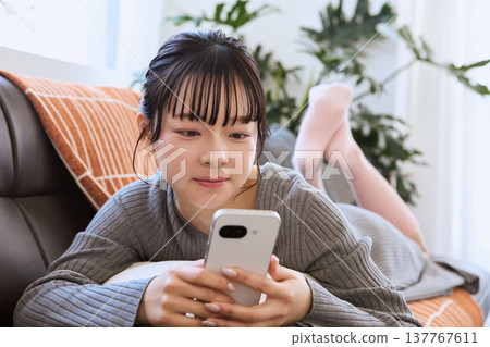 一位女士戴著耳機，在客廳享受智慧型手機帶來的輕鬆生活。 137767611