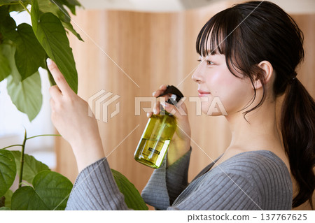 一位年輕女子正在照顧室內植物 一位年輕女子正在照顧室內植物 137767625