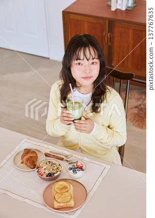 A young woman enjoying a healthy breakfast scene with a matcha latte. 137767635