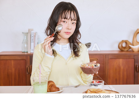 一位年輕女子正在享用一碗健康的巴西莓早餐。 137767636