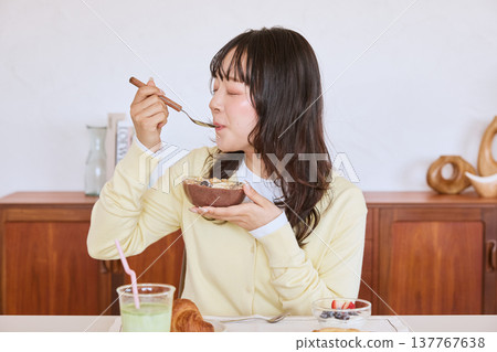 A young woman enjoying a healthy breakfast scene of an acai bowl. A young woman enjoying a healthy breakfast scene of an acai bowl. 137767638