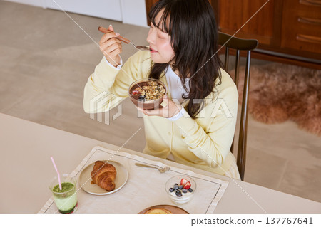 A young woman enjoying a healthy breakfast scene of an acai bowl. A young woman enjoying a healthy breakfast scene of an acai bowl. 137767641