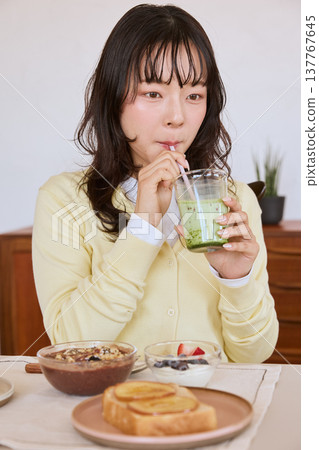 一位年輕女子正在享用抹茶拿鐵，享用健康的早餐。 137767645