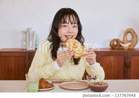 A young woman eating toast for breakfast at home. A young woman eating toast for breakfast at home. 137767648