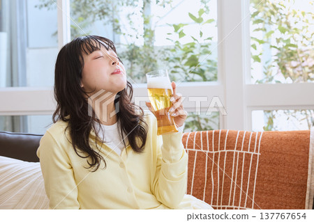 A young woman relaxing with a beer on her day off. A young woman relaxing with a beer on her day off. 137767654