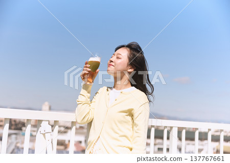 A young woman enjoying a beer under the blue sky A young woman enjoying a beer under the blue sky 137767661