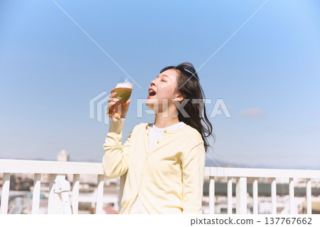 一位年輕女子在藍天下享用啤酒 一位年輕女子在藍天下享用啤酒 137767662