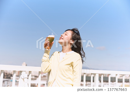 A young woman enjoying a beer under the blue sky A young woman enjoying a beer under the blue sky 137767663