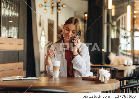 Conversation by phone, talking. Young woman is in the cafe at daytime Conversation by phone, talking. Young woman is in the cafe at daytime 137767690