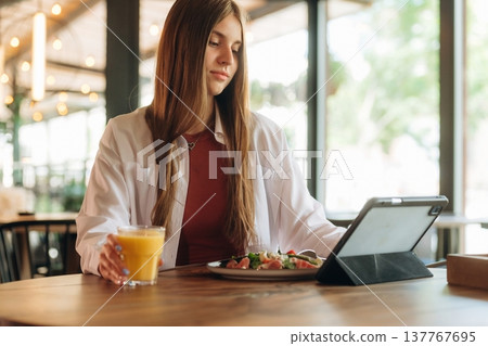 Using digital tablet, sitting, front view. Young woman is in the cafe at daytime 137767695