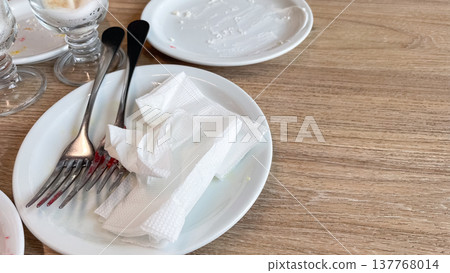 Close-up of dirty dishes and used napkins on a wooden table with copy space for text after breakfast Close-up of dirty dishes and used napkins on a wooden table with copy space for text after breakfast 137768014