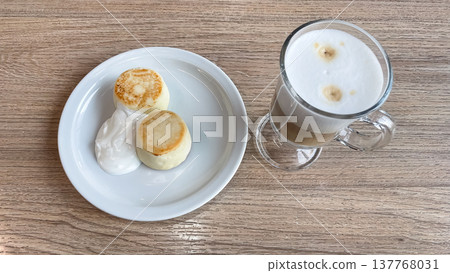 Soft morning light hits golden syrniki and a creamy latte for a cozy, peaceful breakfast moment Soft morning light hits golden syrniki and a creamy latte for a cozy, peaceful breakfast moment 137768031