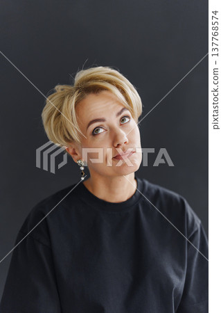 Woman looking up with a thoughtful expression in a dark background Woman looking up with a thoughtful expression in a dark background 137768574