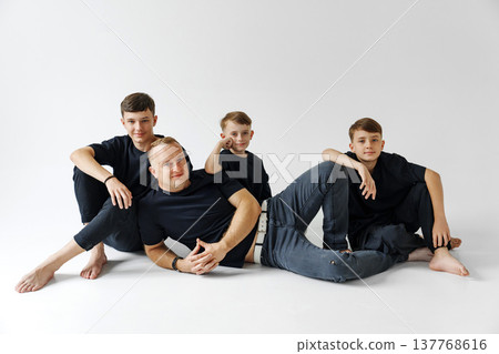 Family of four poses together in a studio setting during daytime Family of four poses together in a studio setting during daytime 137768616