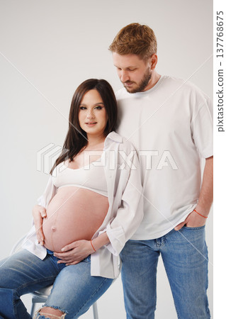 Expecting parents pose happily during a studio session Expecting parents pose happily during a studio session 137768675