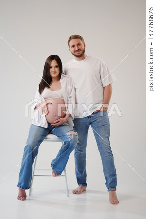 Expecting parents pose happily in bright studio setting Expecting parents pose happily in bright studio setting 137768676