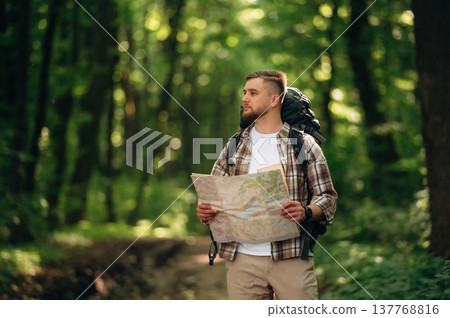 Map in hands. Male tourist is with backpack in the forest Map in hands. Male tourist is with backpack in the forest 137768816