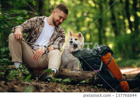 Break time, sitting. Man tourist is with his dog in the forest 137768844