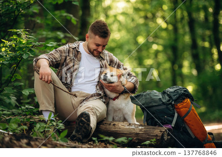 Break time, sitting. Man tourist is with his dog in the forest Break time, sitting. Man tourist is with his dog in the forest 137768846
