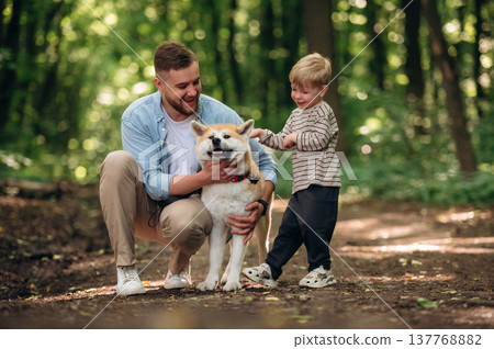 Cute pet, sitting and having fun. Father with son and dog are in the forest Cute pet, sitting and having fun. Father with son and dog are in the forest 137768882