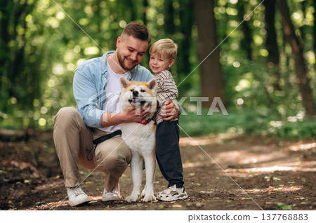 Cute pet, sitting and having fun. Father with son and dog are in the forest 137768883