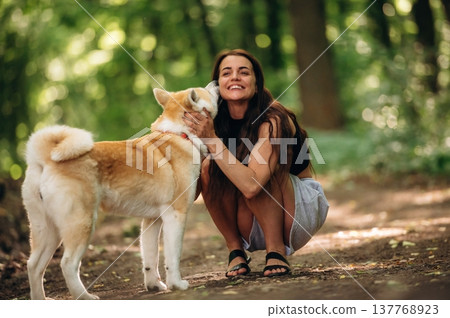Happy woman is with Shiba Inu dog in the forest Happy woman is with Shiba Inu dog in the forest 137768923